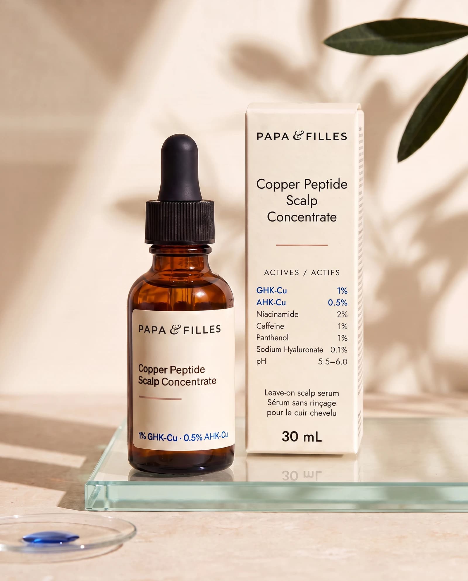 Copper Peptide Scalp Concentrate in its amber bottle and cream carton, on a glass plinth in botanical light