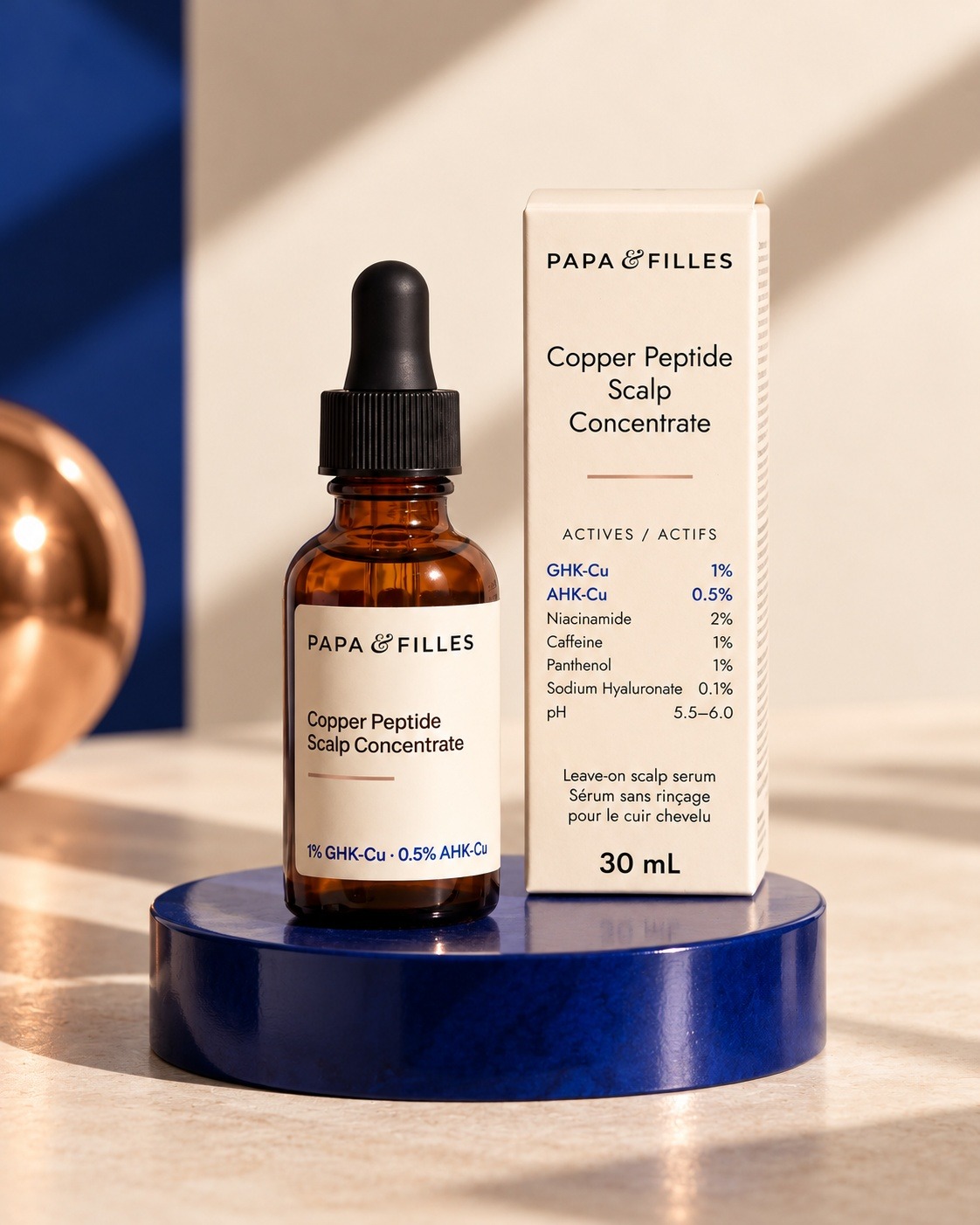 Papa & Filles Dual Peptide Scalp Serum, 30 mL amber dropper bottle and carton on a navy pedestal